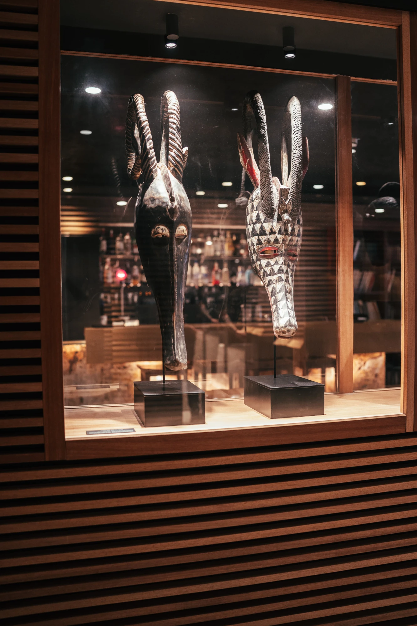 Se ve una vitrina con esculturas africanas iluminadas en una sala interior.
