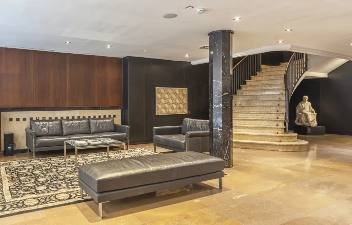 Se ve una zona de estar con sofás, una mesa auxiliar y una escalera de piedra en un espacio interior.