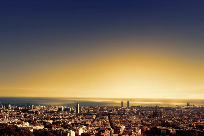 Vista panorámica de una ciudad al atardecer con luces encendidas y cielo en tonos azul y dorado.