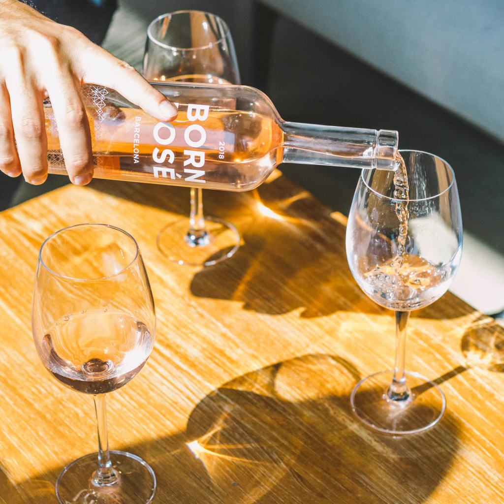 Sirven una botella de vino y tres copas sobre una mesa de madera.