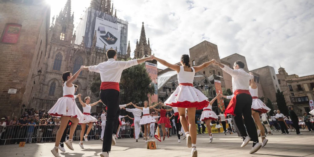 Un gruppo di ballerini in abiti bianchi e rossi si esibisce in una piazza cittadina.