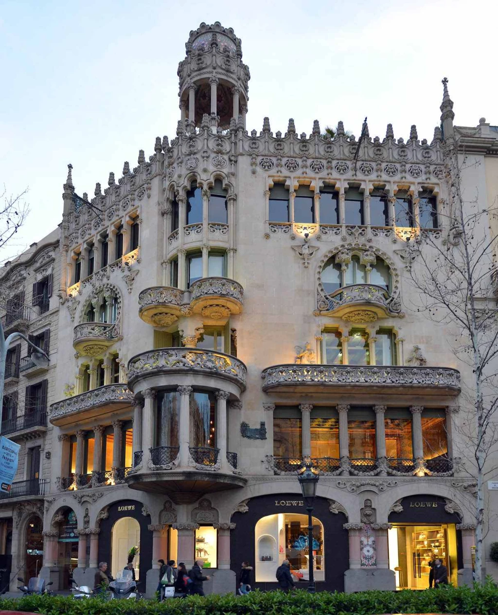 Se ve una fachada modernista con balcones y arcos decorativos sobre la calle.