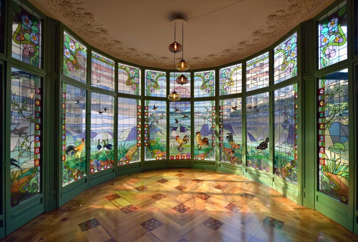 Se ve una sala interior con suelo de mosaico y grandes vitrales en las paredes.