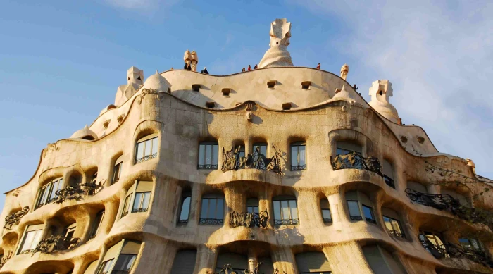 The modernist façade is visible with balconies and flowing shapes beneath a clear sky.