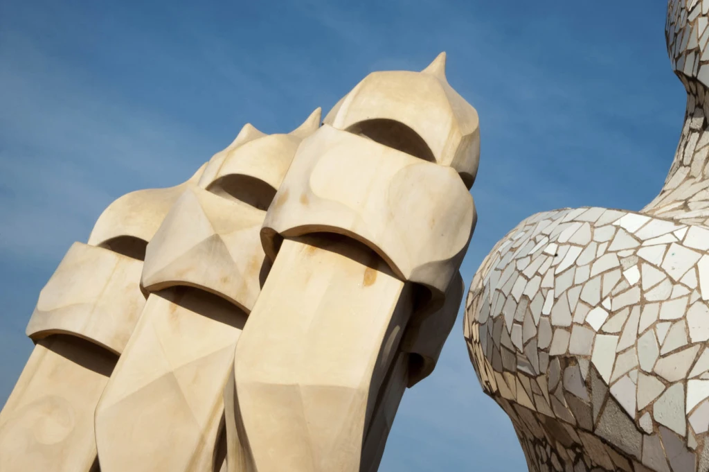 A sculptural detail of the façade of La Pedrera is seen against the blue sky.