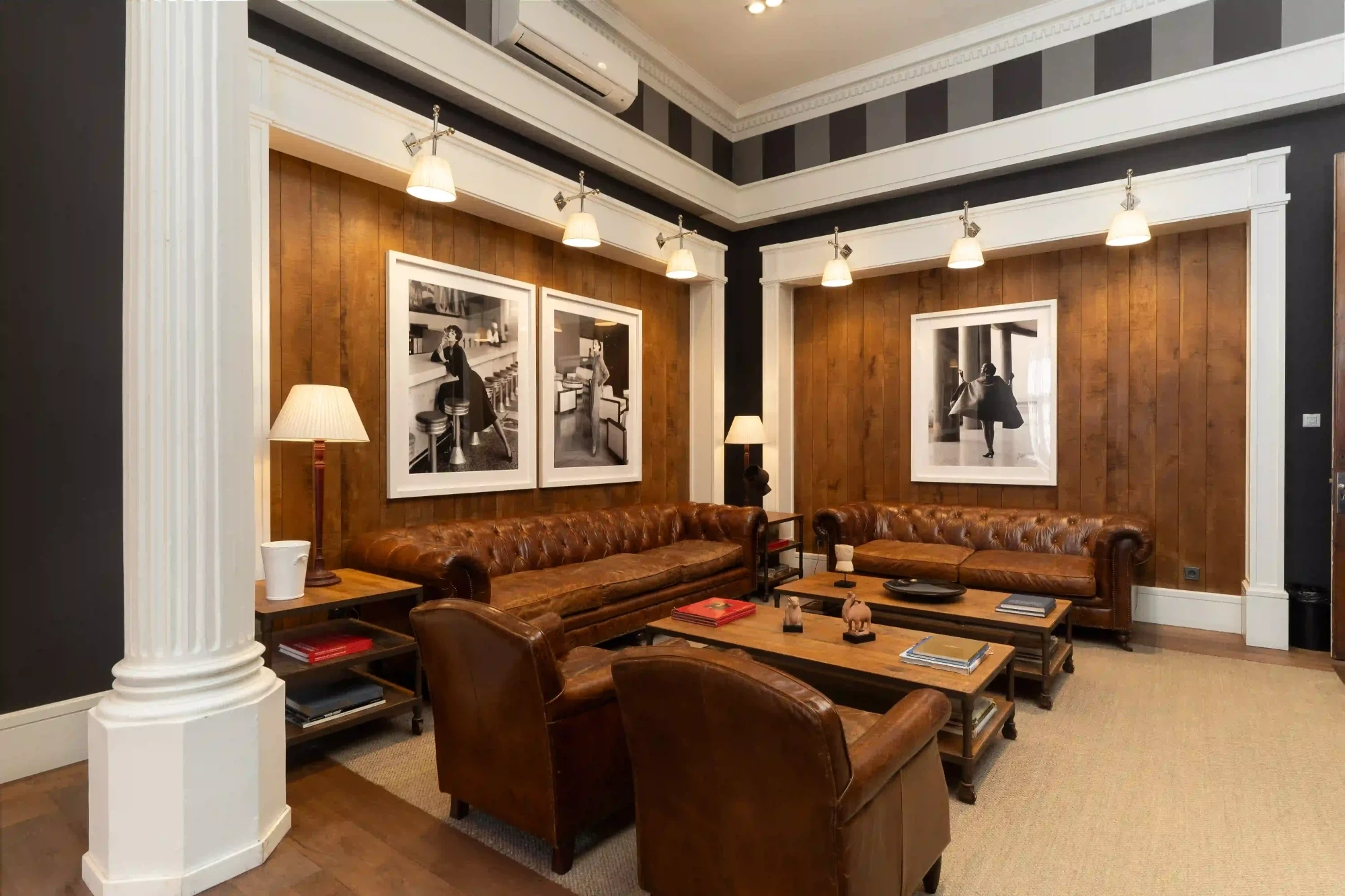 A room with wooden tables, leather chairs, and hanging lamps above the reading area is shown.