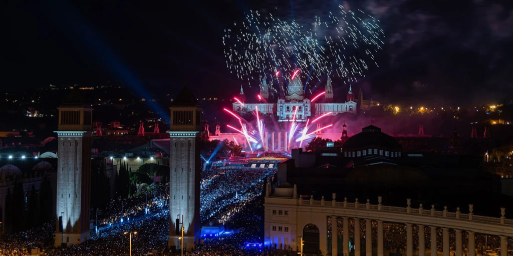On voit un spectacle de feux d’artifice avec des lumières et des étincelles au-dessus d’un environnement urbain nocturne.