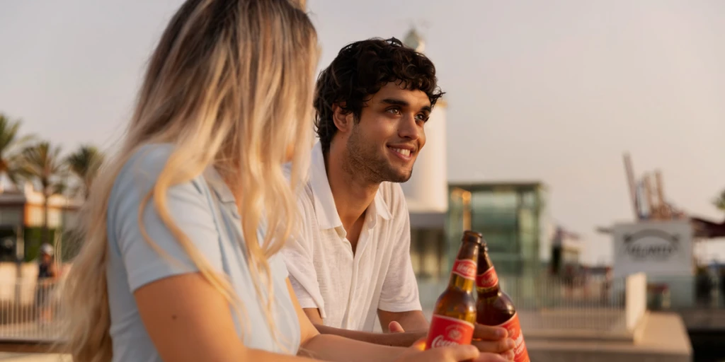 Zwei Personen unterhalten sich auf einer Terrasse im Freien bei Sonnenuntergang.