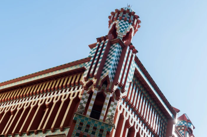Se ve una fachada modernista con una torre decorada y ventanas bajo un cielo despejado.