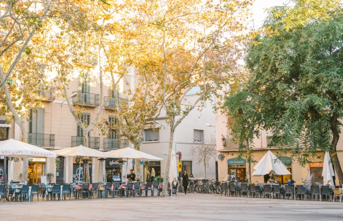 Una vista de una calle en el barrio de Vila de Gracia, con edificios residenciales de estilo clásico y coloridos, que reflejan la arquitectura típica del barrio en Barcelona.