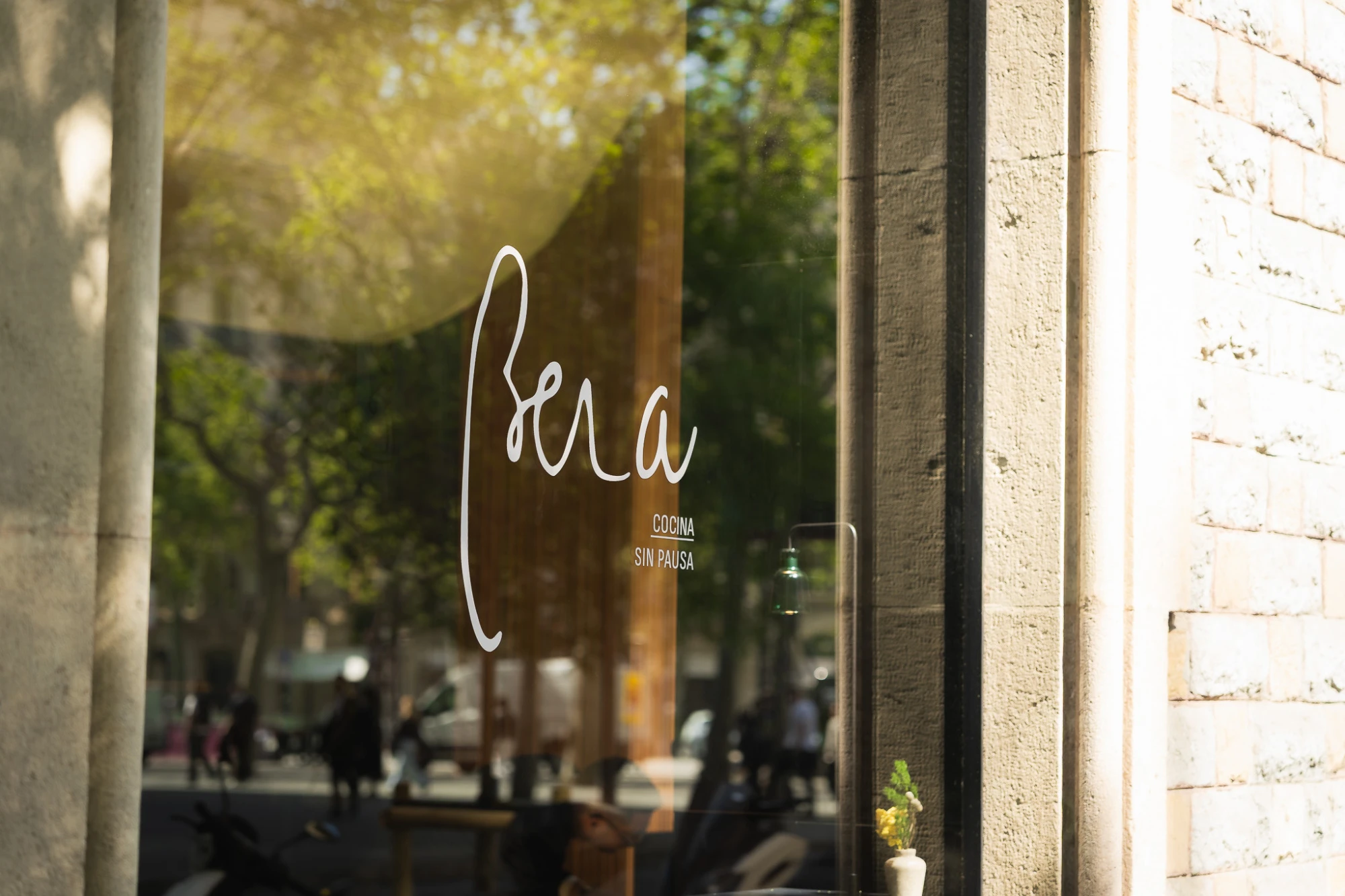 Se ve un ventanal junto a un muro de ladrillo con una mesa y sillas al exterior.