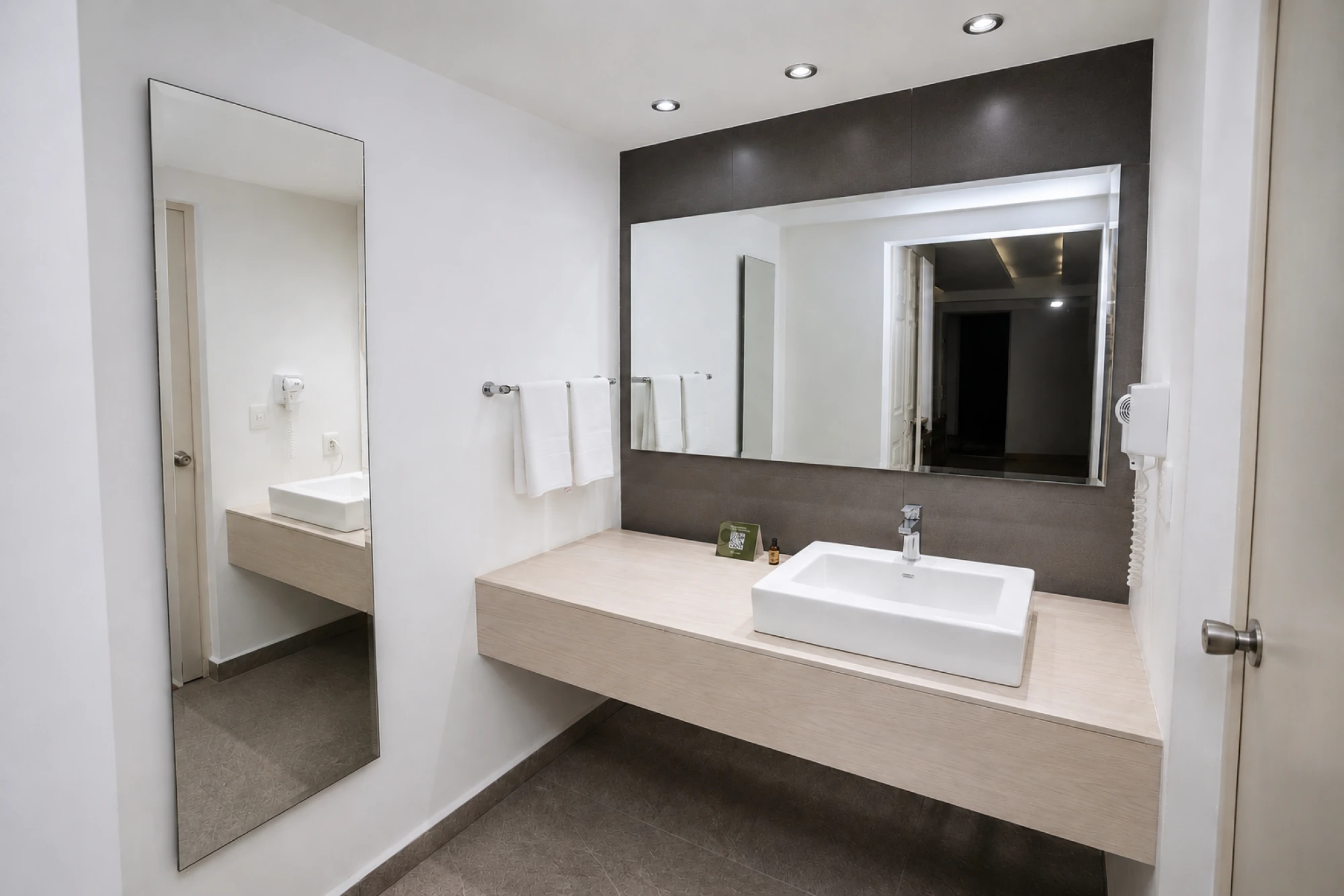 Se ve un baño moderno con doble lavabo empotrado y espejo iluminado sobre una encimera de madera clara.