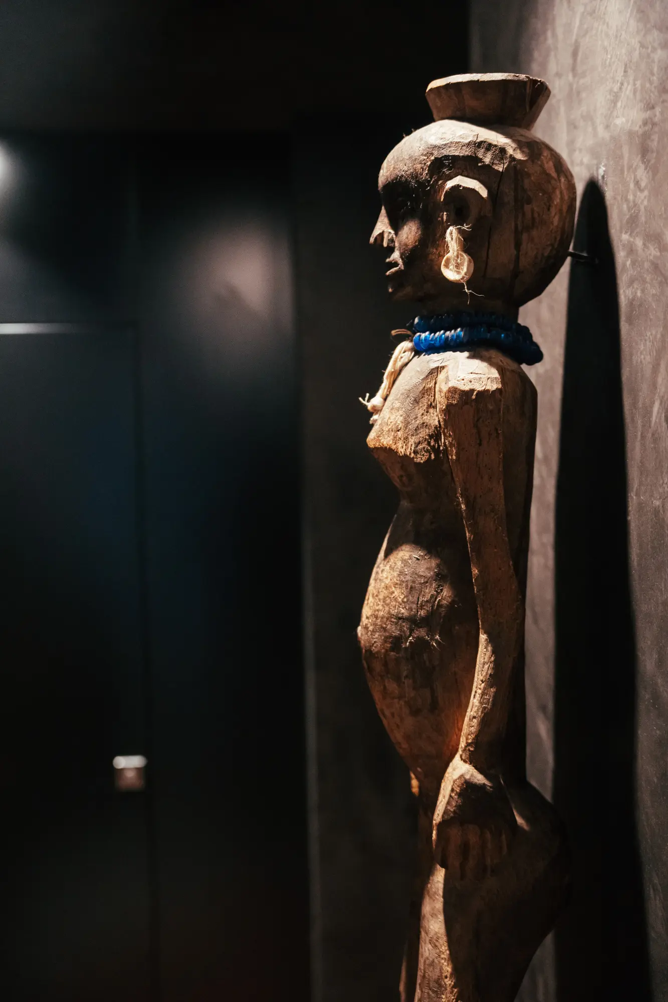 Se ve una escultura de madera tallada con detalles decorativos sobre un fondo oscuro.