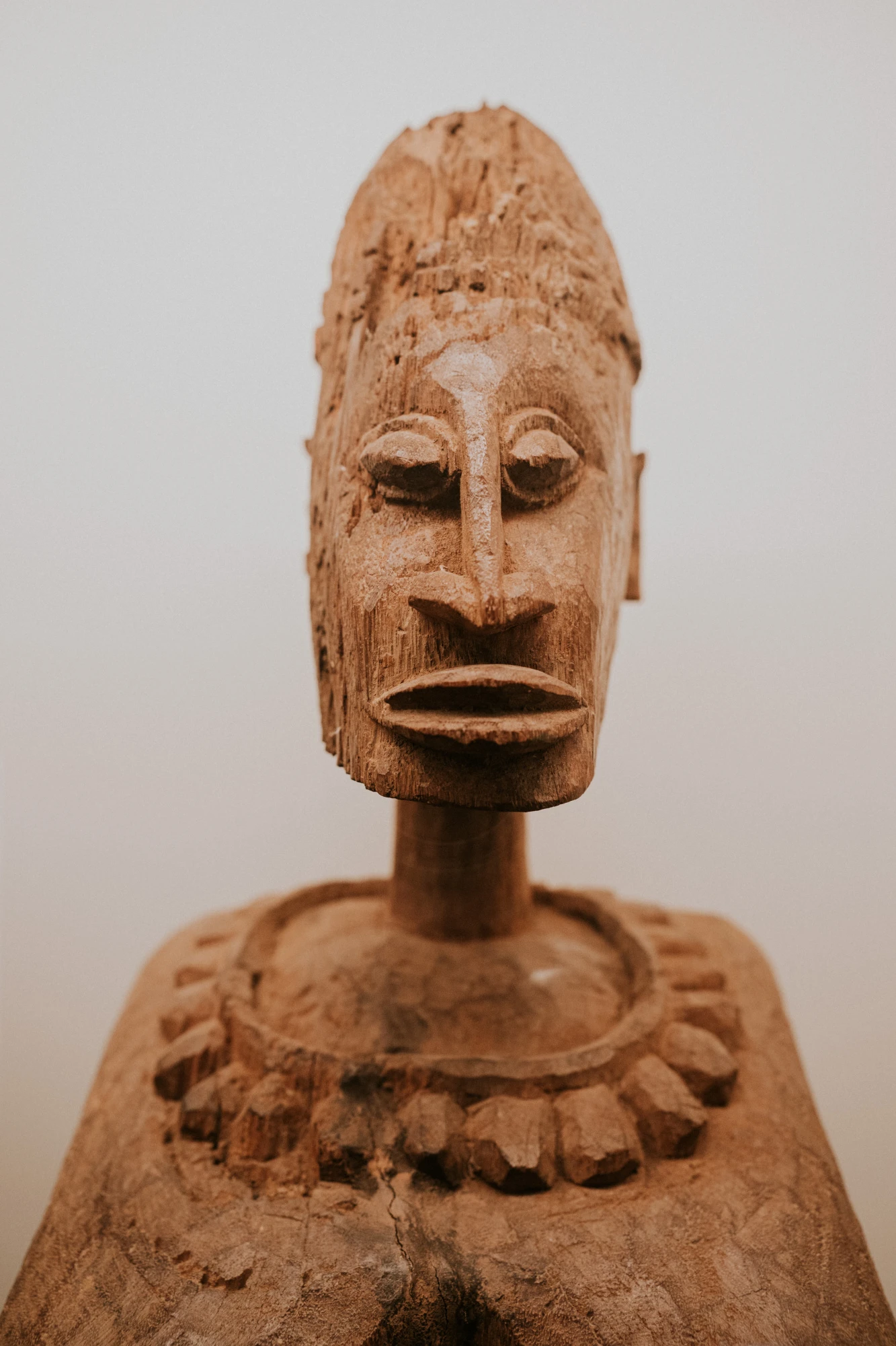 Se ve una escultura africana de madera tallada sobre un fondo claro.