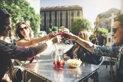 Un grupo de personas brinda con bebidas sobre una mesa en una terraza al aire libre.