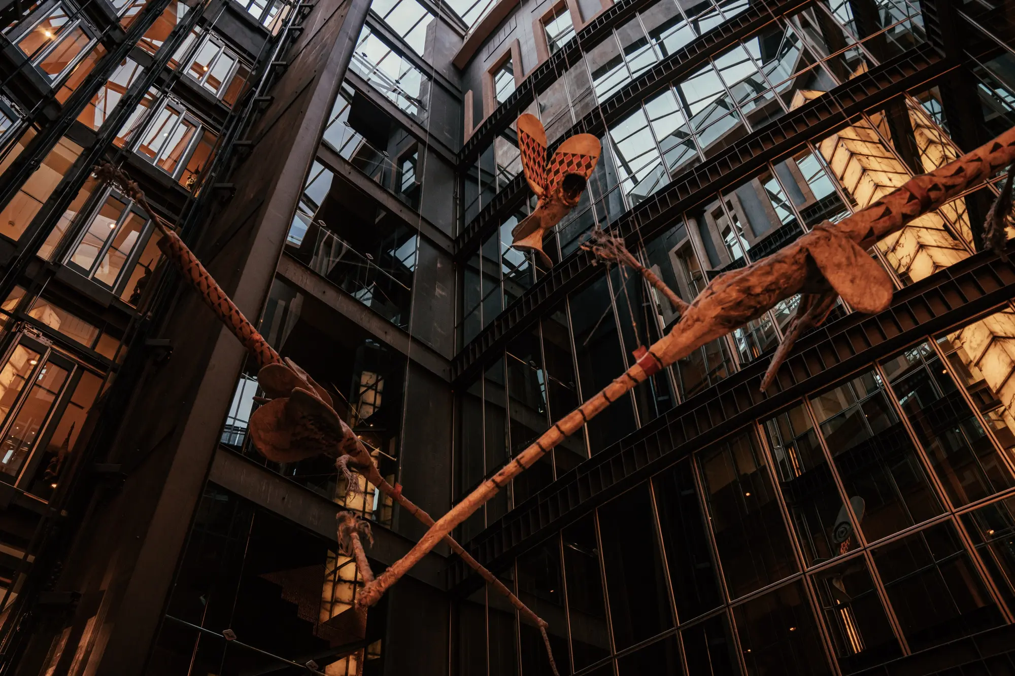 Se ve un pasillo interior con barandillas de metal y pasarelas que conectan varios niveles del edificio.