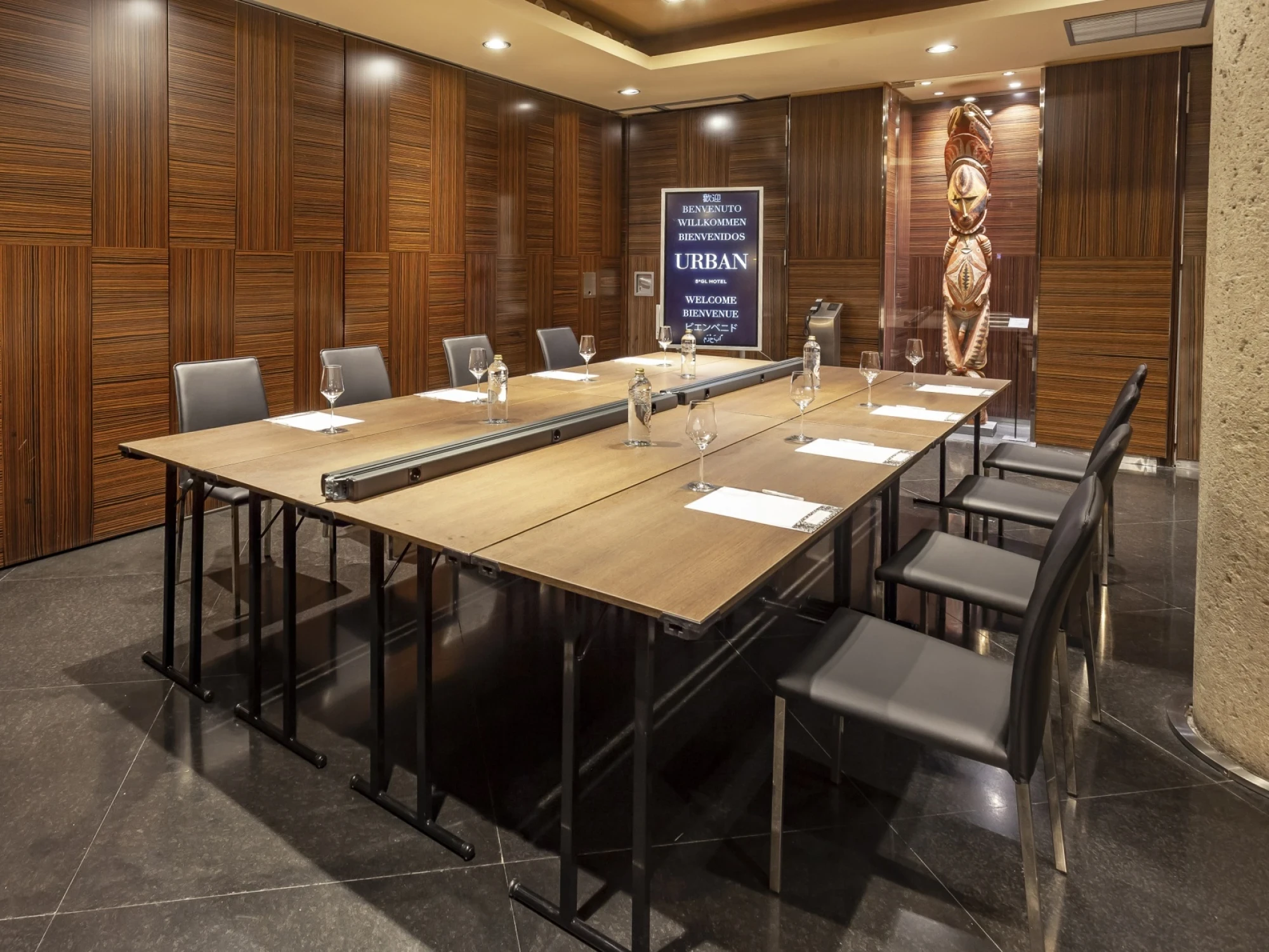 Sala de reuniones con mesa larga, sillas y paneles de madera en la pared.