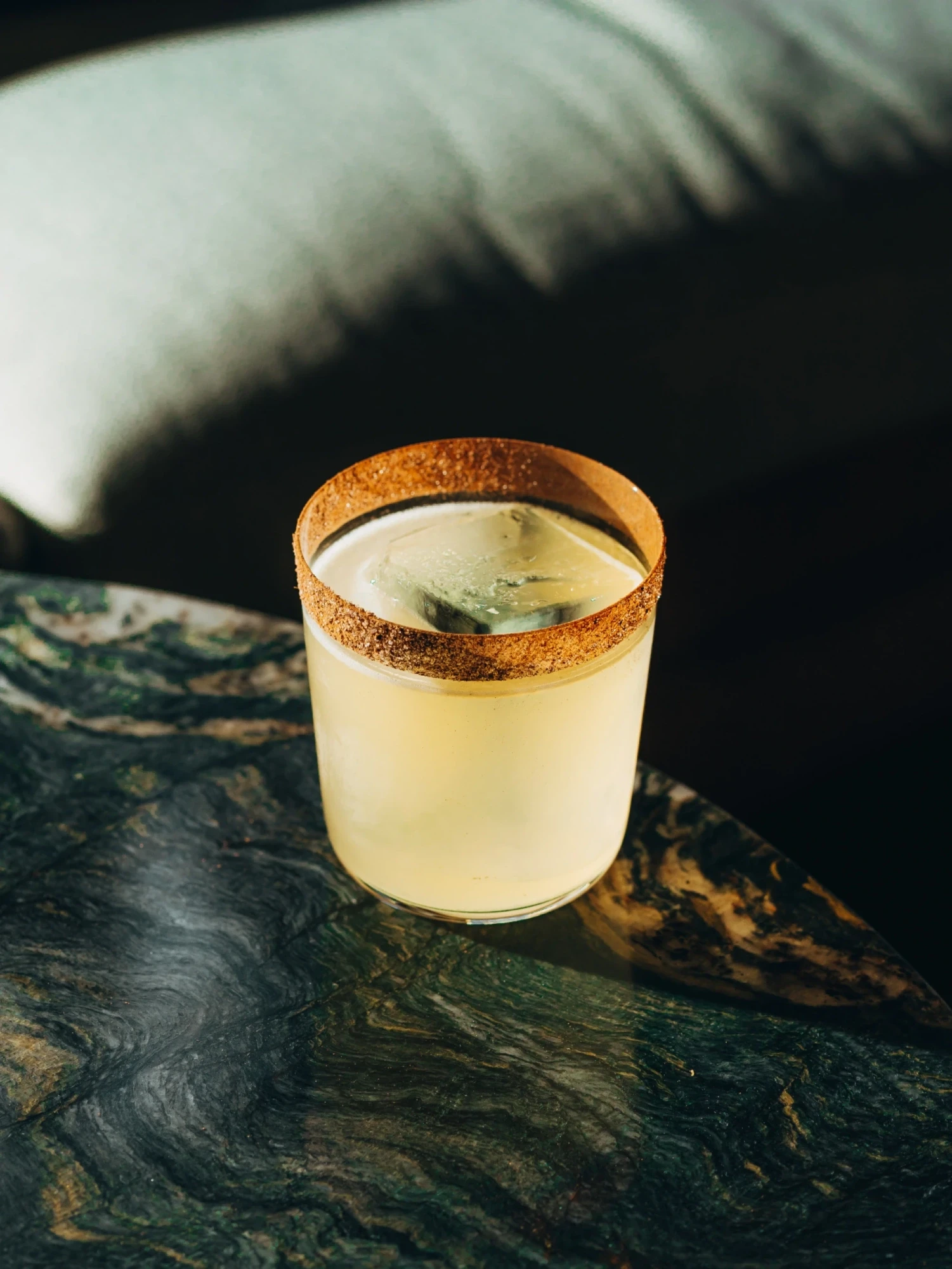 Se ve una copa con bebida cremosa y espuma sobre una mesa de madera oscura.