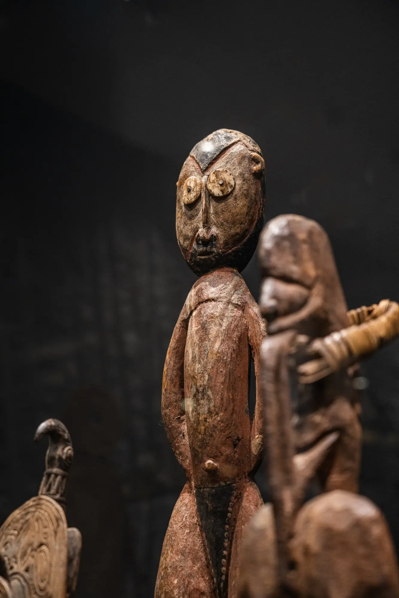 Se ven varias esculturas de figuras humanas de estilo antiguo sobre un fondo oscuro.