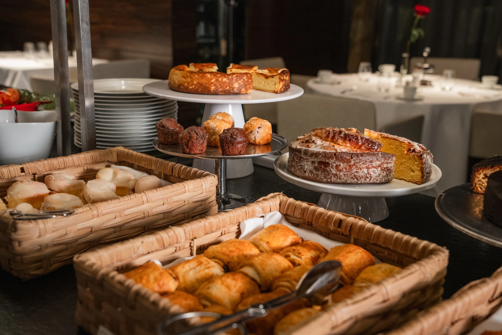 Se ven bandejas con bollería y platos en un buffet de desayuno.