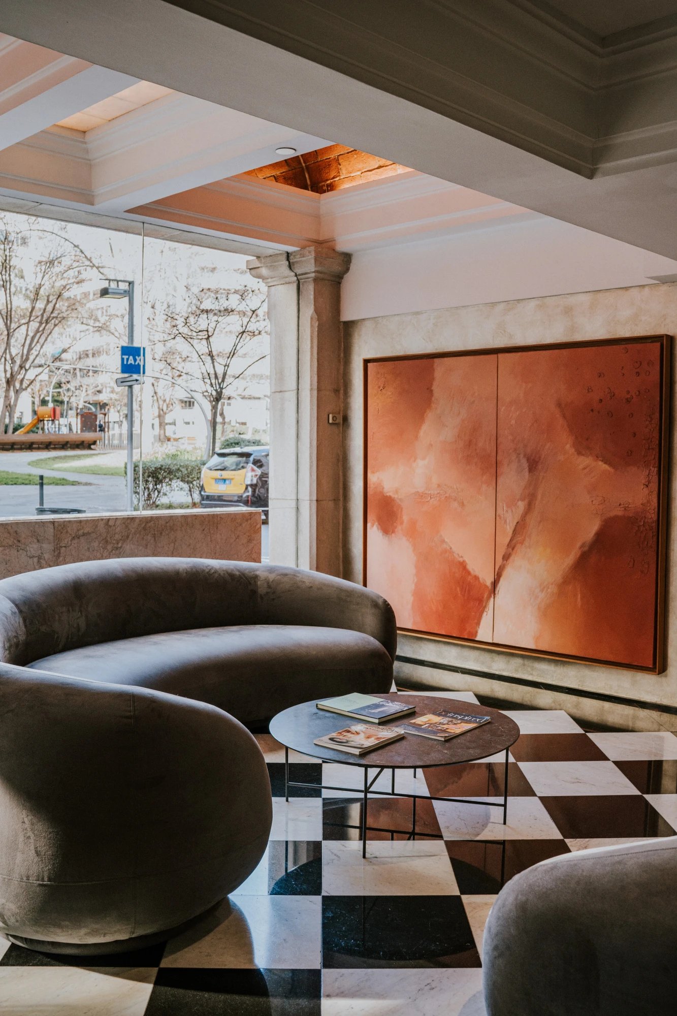 Se ve una zona de estar con sillones, una mesa baja y una pared con un cuadro grande.
