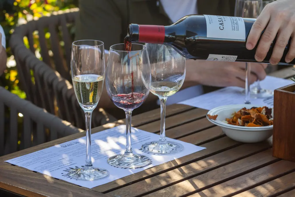 You can see a wooden table with wine glasses and a bottle while a meal is being served.