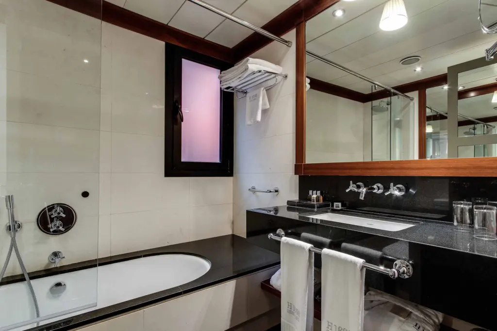 S'hi veu un bany amb banyera, lavabo doble i un mirall amb il·luminació.