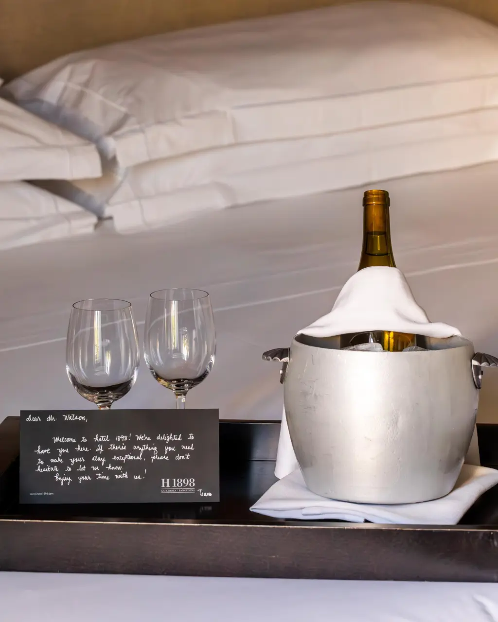 A dark-colored wine bottle, likely made of glass, with a visible label, placed on a surface. The image conveys a sense of elegance and sophistication, ideal for promoting wine services in a hotel.