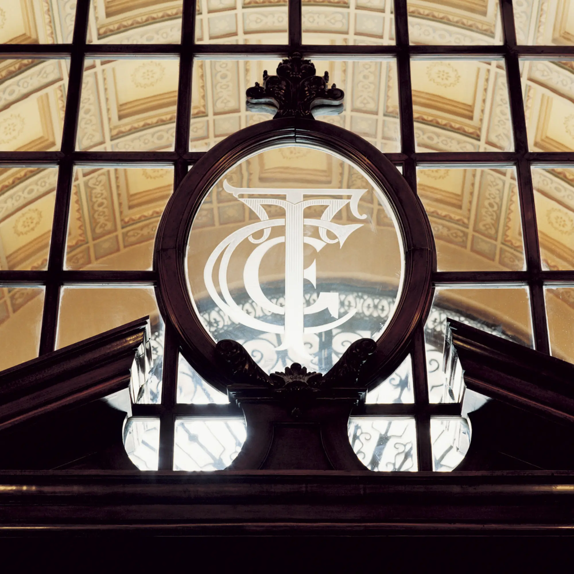 Se ve una entrada con una ventana de vidrio decorada y un marco oscuro sobre un umbral.