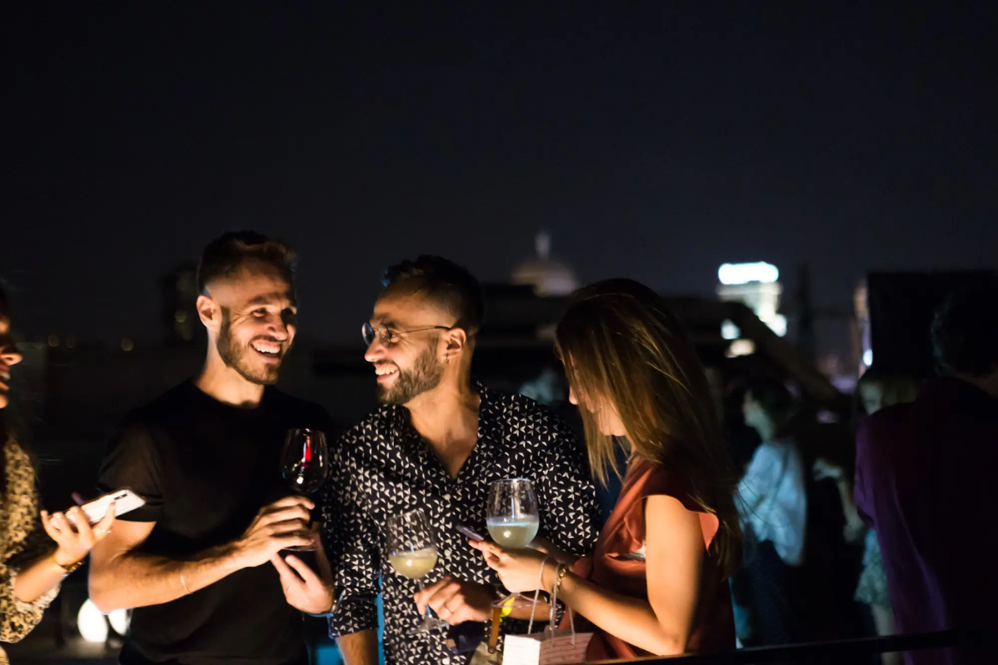 Mehrere Personen stoßen bei einer abendlichen Veranstaltung im Freien mit Gläsern an.