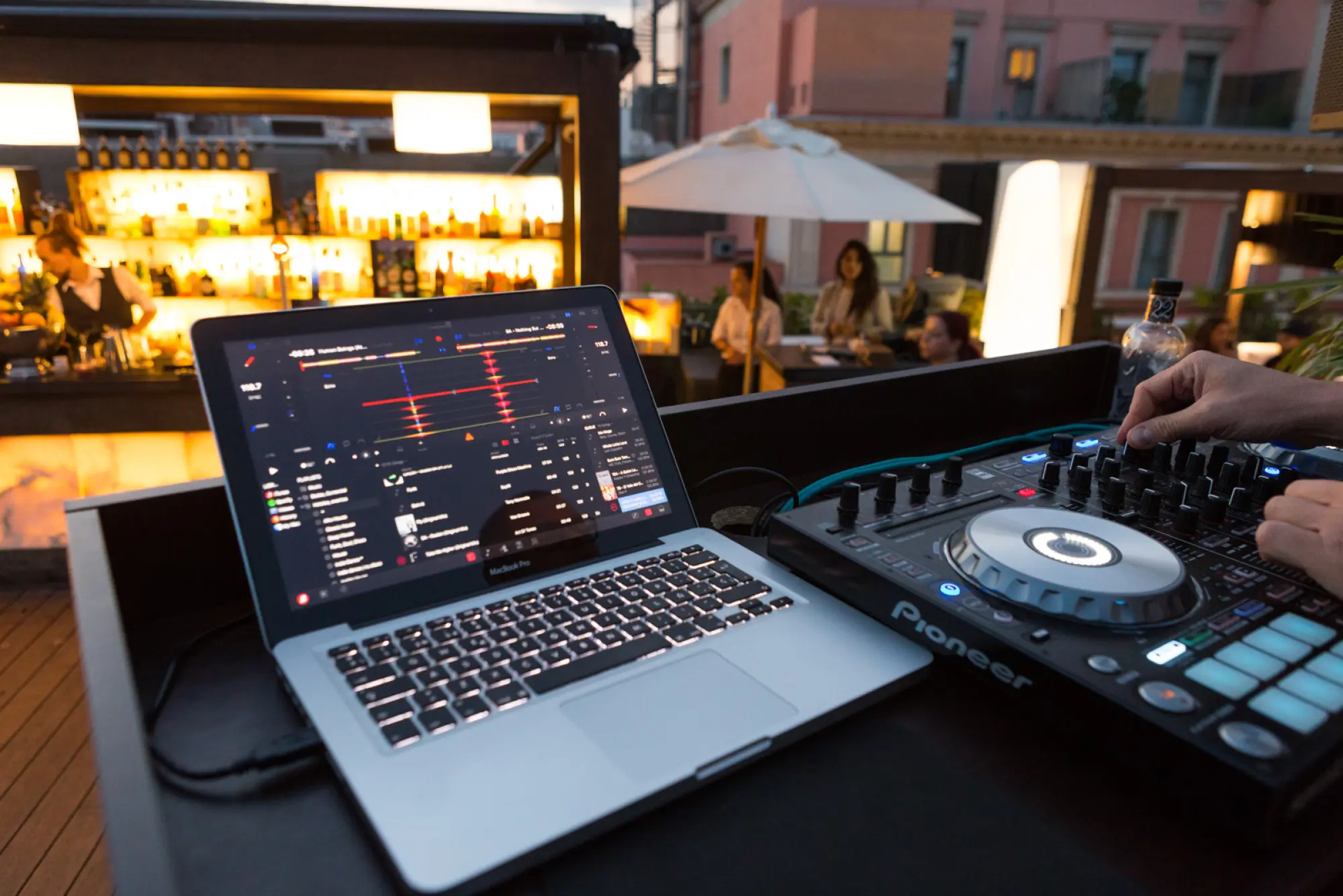 Bei einer Veranstaltung im Freien ist ein Tisch mit einem Laptop und einem DJ-Controller zu sehen.