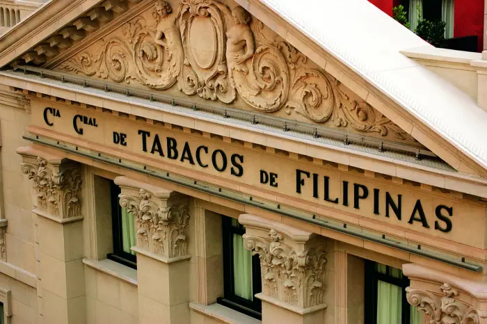 Видно фасад здания с резным декором и вывеской с надписью TABACOS DE FILIPINAS.