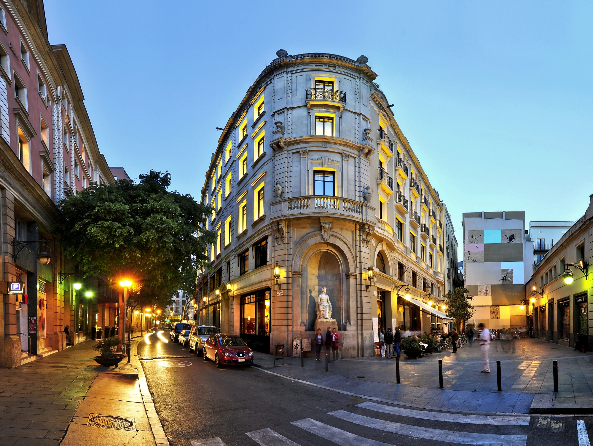 La imagen muestra la fachada de un hotel con un diseño moderno y elegante, con detalles en piedra y grandes ventanas que permiten la entrada de luz natural.