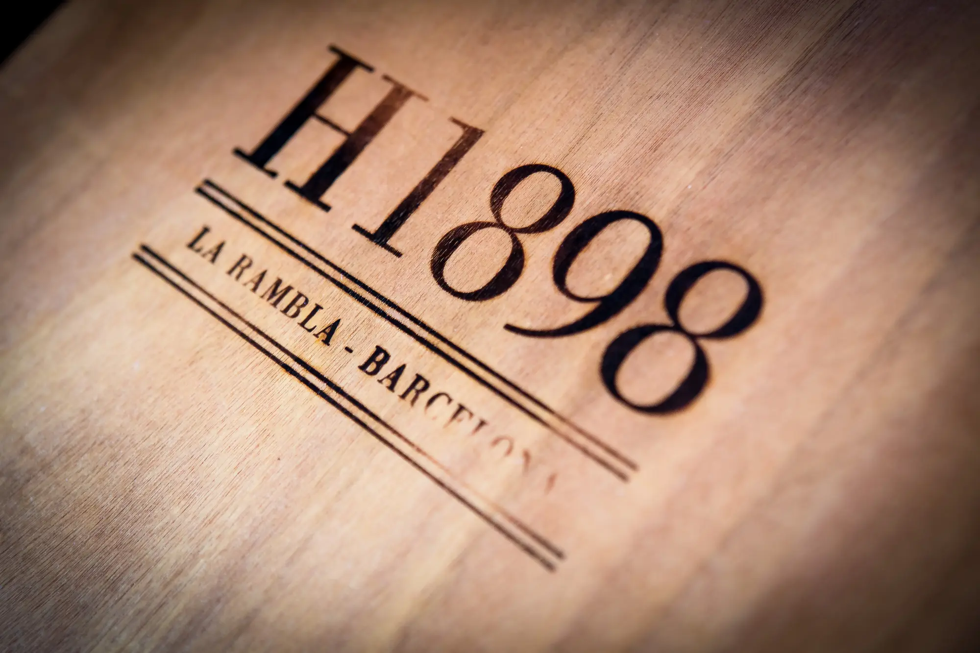 Se ve un logotipo con el texto “H1898” y “LA RAMBLA BARCELO” sobre un fondo claro.