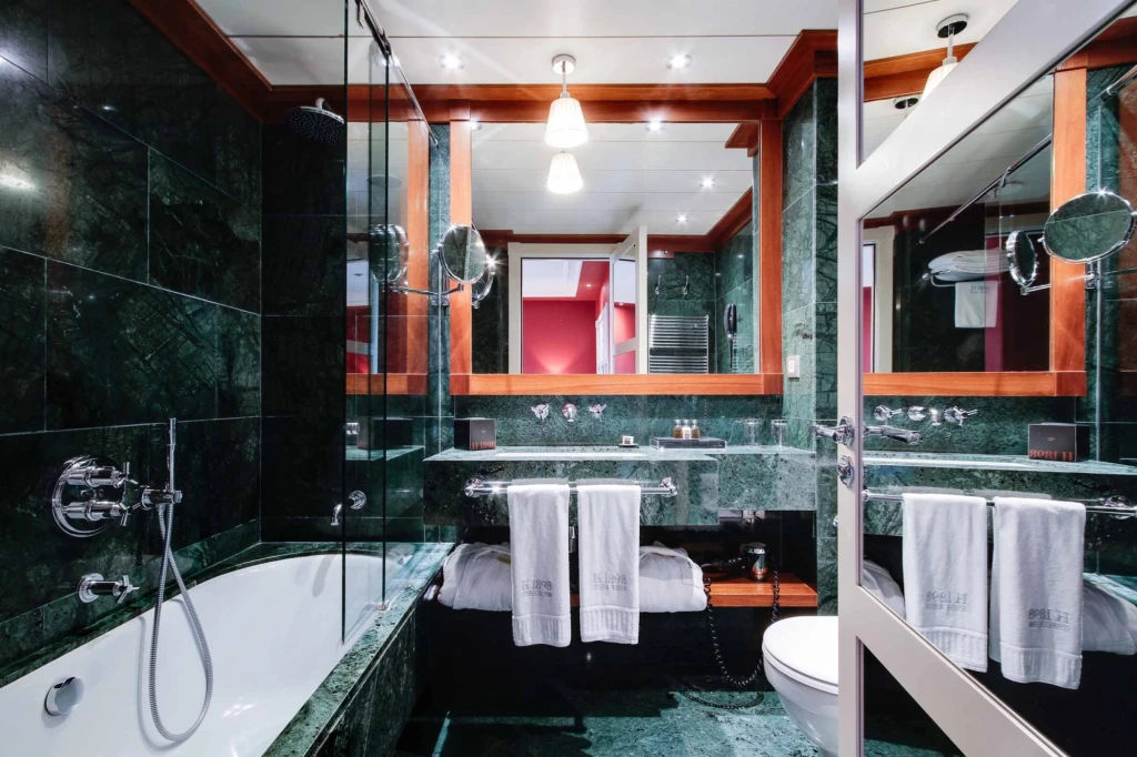 A modern bathroom is shown with a bathtub, glass shower, and sink with white towels.