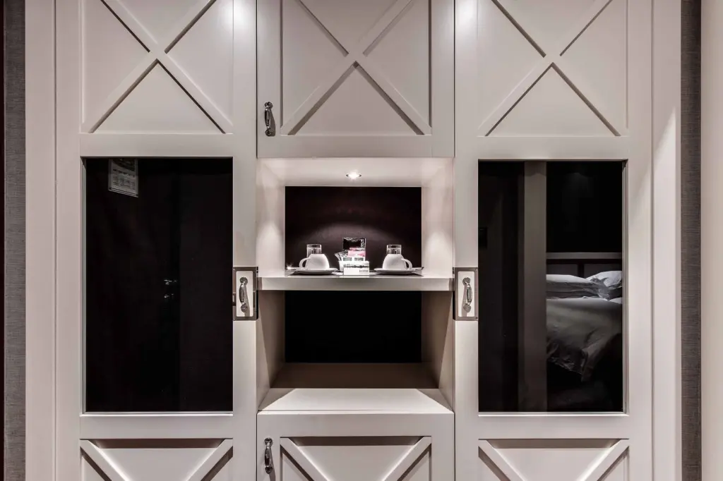 Se ve una pared con nicho decorativo y dos puertas abiertas que muestran camas en el interior.
