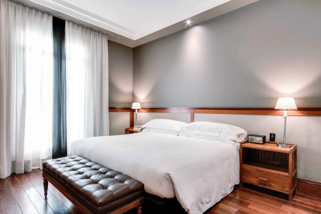 Mostra una camera con un letto matrimoniale, un comodino e tende vicino a una finestra.