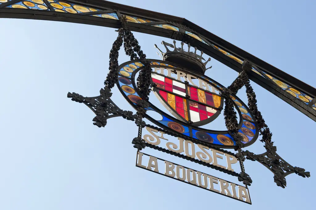 Si vede un cartello di La Boqueria con un emblema circolare su una struttura metallica.