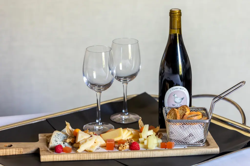 An elegant presentation of a glass of red wine and a selection of assorted cheeses, ideal for enjoying in a sophisticated and cozy setting.
