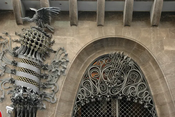 Se ve una puerta arqueada de hierro forjado y un esqueleto de dinosaurio en una sala interior.