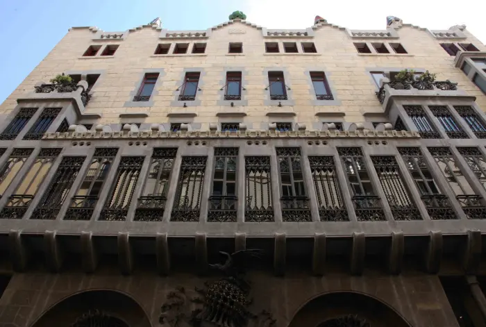 Si vede la facciata in pietra di un edificio con finestre e archi al piano terra.