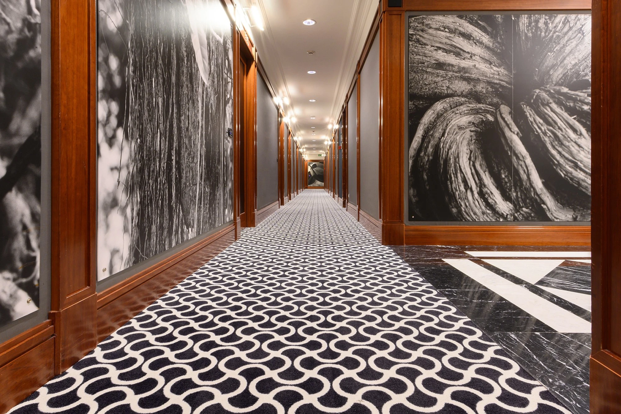 Un corridoio presenta una moquette a motivi e pareti con pannelli decorativi in bianco e nero.