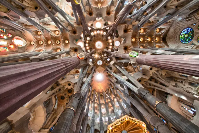 Es veu l’interior de la basílica amb columnes i vitralls sota una volta decorada.