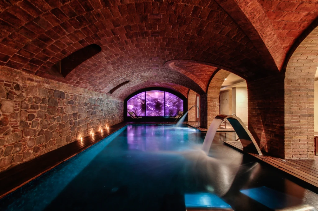 Un lujoso spa con un diseño moderno, que presenta una piscina interior de agua cristalina y áreas de descanso elegantes, ideal para relajarse y disfrutar de servicios de bienestar.