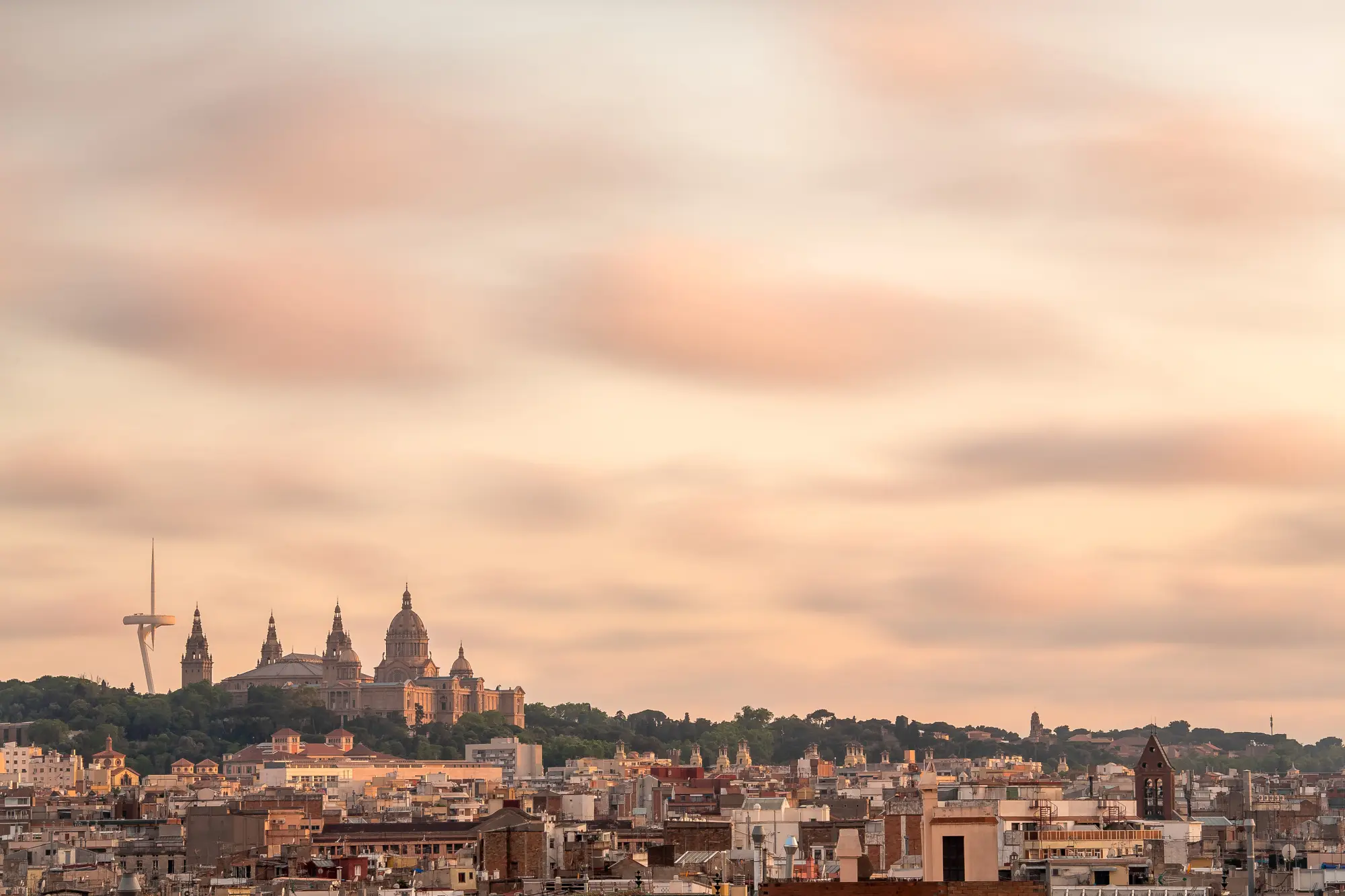 A cityscape with buildings and a cloudy sky at sunset.