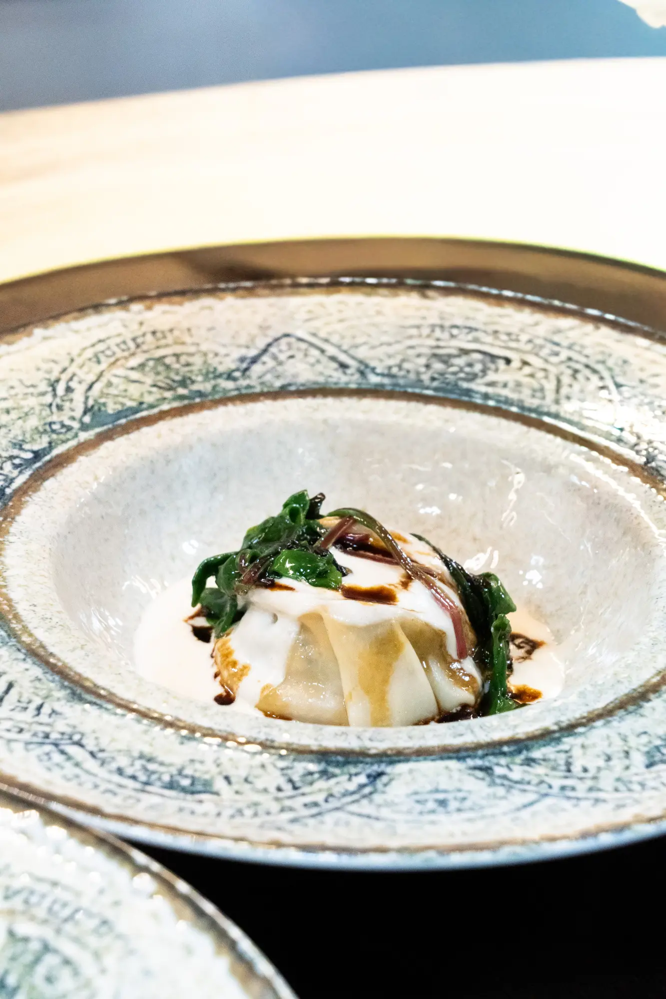 Una imagen que muestra ravioli relleno de boletus, acompañado de salsa de cebolleta y acelgas rojas, presentado en un plato elegante y apetitoso.