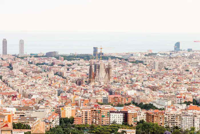 Se ve una vista panorámica de Barcelona con edificios y la Sagrada Família al centro.