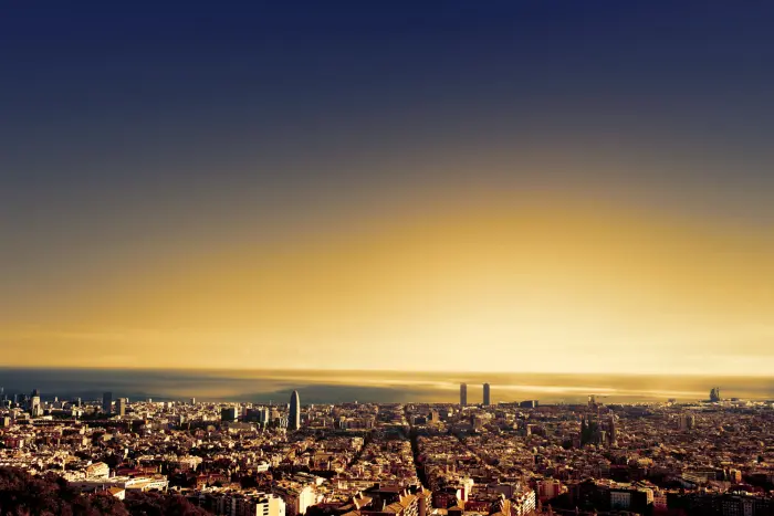 Vista panorámica de una ciudad al atardecer con luces encendidas y cielo en tonos azul y dorado.
