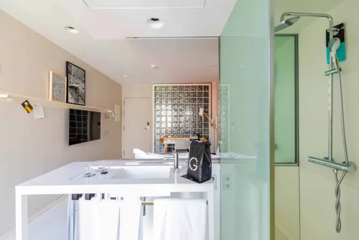 Se ve un baño moderno con ducha de vidrio y un lavabo blanco con encimera.