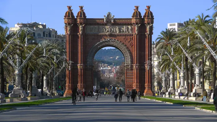 Se ve el arco de triunfo con palmeras y una avenida al frente bajo un cielo despejado.